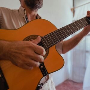 A detailed image of a musician strumming an acoustic guitar indoors.