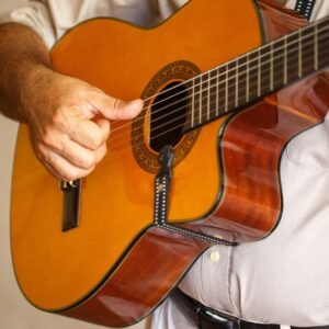 Detailed view of a musician strumming an acoustic guitar indoors.